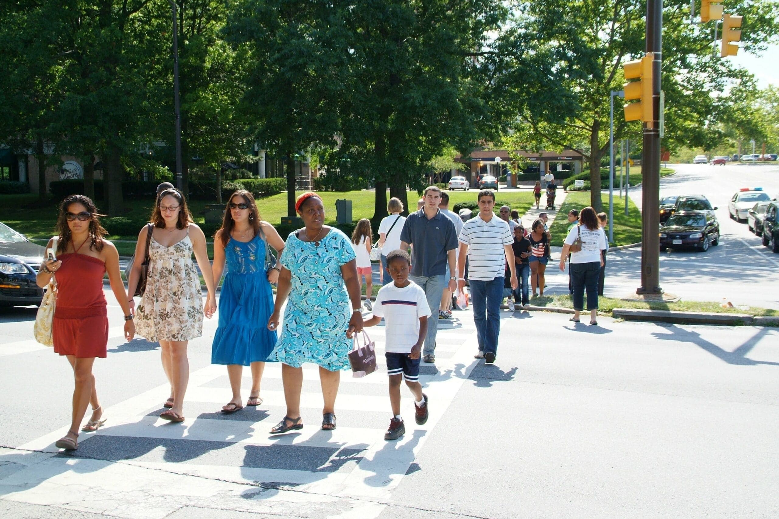 A diverse group of people crosses the street on a marked and signalized crosswalk